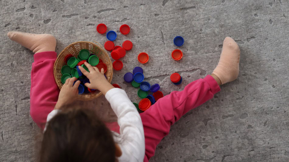 Psicomotricidad en la etapa infantil niña jugando tapas de botellas de plástico