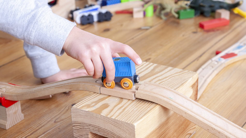 Psicomotricidad en la etapa infantil niño jugando con un tren de railes de madera