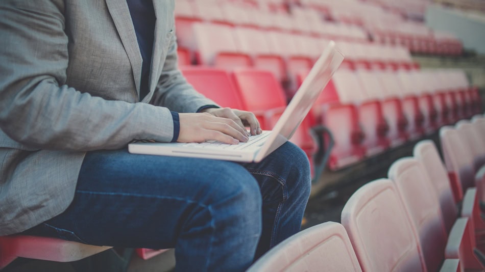 Administrador deportivo en las gradas de un estadio usando un portátil